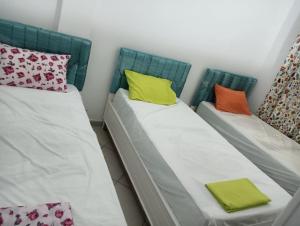 2 Betten mit bunten Kissen nebeneinander sitzen in der Unterkunft Maison a louer à kelibia in Kelibia