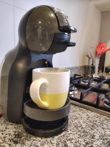 Una cafetera está haciendo una taza de café en un mostrador en Apartamento centrico, en Minas