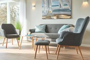 a living room with a couch and two chairs and a table at Mein Ankerpunkt in Simonsberg