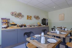 a dining room with wooden tables and a kitchen at Hôtel de la Tour in La Tour-du-Pin