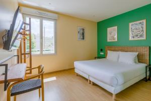 ein Schlafzimmer mit einem weißen Bett und einer grünen Wand in der Unterkunft Hôtel de la Tour in La Tour-du-Pin