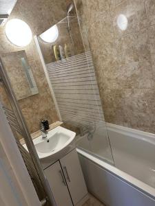 a bathroom with a sink and a shower with a mirror at Cosy 2 Bedroom Apartment in South West London in London