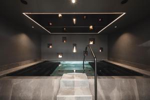 a swimming pool with stairs and lights on the ceiling at Hotel Steger-Dellai in Alpe di Siusi