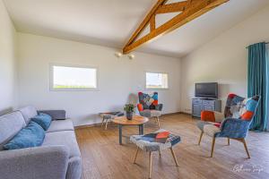a living room with a couch and chairs and a tv at Les Petits Faulongs in Sauviac