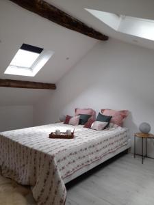 a white bedroom with a large bed with pink pillows at Creusoé in Saint-Marc-à-Frongier