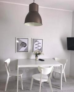 a white dining room table with white chairs and a lamp at Willa Relaksowa in Karwia