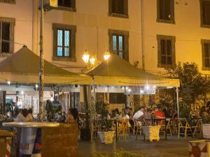 a group of people sitting at tables under umbrellas at C sta o mar for in Naples