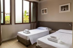 two beds in a room with two windows at Plus Florence in Florence