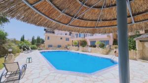 a swimming pool with a straw umbrella and a resort at STAY Tala Sea View Apartment in Tala