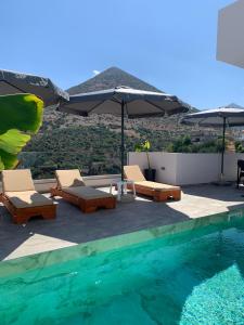 a swimming pool with chairs and umbrellas on a roof at White Boutique Homes - Serenity in Metókhion Apisianá