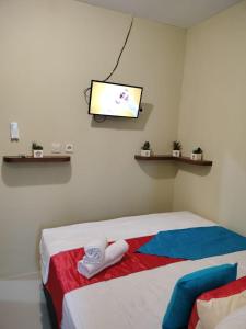 Maluku Residence Syariah في امبون: غرفة مع سرير وتلفزيون على الحائط