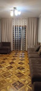 Una sala de estar con un sofá y suelo de madera. en Yunusabad apartment 19, 1, en Magaldarkhan