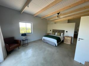 um quarto com uma cama, uma cadeira e uma janela em Windon vineyard farmhouse em Stellenbosch