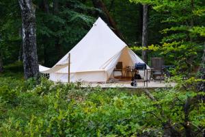 une tente blanche avec une terrasse dans les bois dans l'établissement Glamping Bolmen, Seaview, free canoe, à Odensjö
