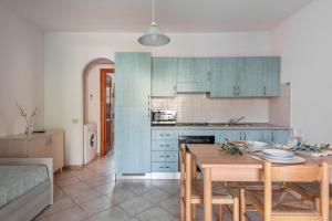 a kitchen with blue cabinets and a table with chairs at ISA-Apartments with air conditioning and external outdoor space in Budoni, at only 300 m from the beach in Budoni