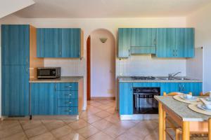 a kitchen with blue cabinets and a table with a microwave at ISA-Apartments with air conditioning and external outdoor space in Budoni, at only 300 m from the beach in Budoni