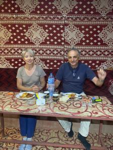 a man and a woman sitting at a table with food at Walid Bedouin Camp in Wadi Rum