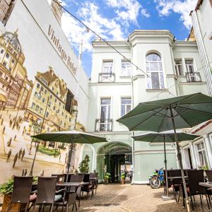 a patio with tables and umbrellas in front of a building at Vintage Art Hotel in Odesa
