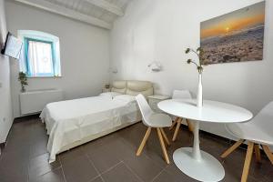 a white bedroom with a bed and a table and chairs at B&B Dimora Orrù in Càbras