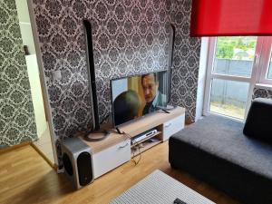 a living room with a flat screen tv and a bed at Vienības in Krāslava