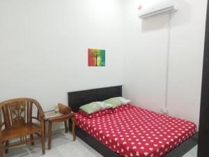 a bedroom with a bed with a red blanket and a chair at Bushra Guest House, Batu Pahat in Batu Pahat
