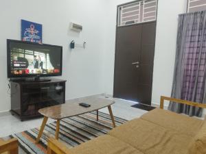 sala de estar con sofá, TV y mesa en Bushra Guest House, Batu Pahat, en Batu Pahat