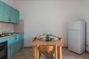 a kitchen with a wooden table and a white refrigerator at ISA-Apartments with air conditioning and external outdoor space in Budoni, at only 300 m from the beach in Budoni