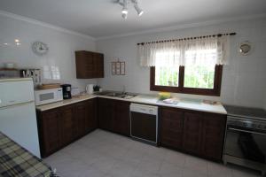 una cocina con armarios de madera y un aparato blanco en Paraiso Terrenal 8 - holiday home with private swimming pool in Costa Blanca, en Benissa