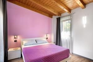 una camera con letto viola e finestra di Agriturismo il Borgo - Rosmarino a Villanova dʼAlbenga