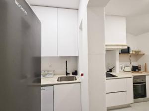 una cocina blanca con armarios blancos y fregadero en green guest house. Figueira da Foz, en Figueira da Foz