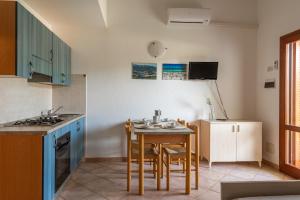a kitchen with a table and chairs in a kitchen at ISA-Apartments with air conditioning and external outdoor space in Budoni, at only 300 m from the beach in Budoni +15 photos