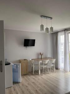 a white dining room with a table and chairs at Willa Relaksowa in Karwia