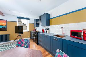 a kitchen with blue cabinets and a red microwave at 89 The Merchants by The House of Danu in Edinburgh
