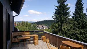 d'un balcon avec des tables et des chaises en bois et un arbre. dans l'établissement Ferienhaus Anjofina Ferienwohnung Kobel, à Altenau