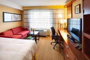 Habitación de hotel con cama, sofá y TV en Courtyard by Marriott London, en London