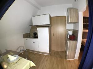 a small kitchen with white cabinets and a refrigerator at Ferienwohnung-Seeblick-Edersee in Waldeck