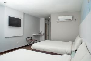 Habitación de hotel con 2 camas y TV en Capital O 90083 Riverfront Inn en Bintulu