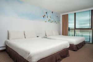 two beds in a hotel room with a window at Capital O 90083 Riverfront Inn in Bintulu
