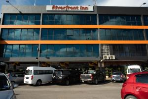 een parkeerplaats met auto's voor een gebouw bij Capital O 90083 Riverfront Inn in Bintulu
