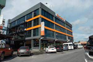 een groot gebouw met auto's geparkeerd op een parkeerplaats bij Capital O 90083 Riverfront Inn in Bintulu