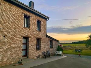 een bakstenen gebouw met stoelen en tafels in een tuin bij Quiétude à la ferme in Houdremont