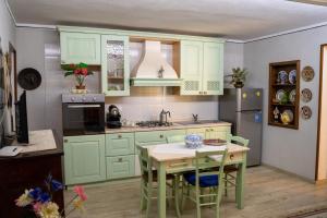 a kitchen with green cabinets and a table with chairs at S'apposentu in Aritzo