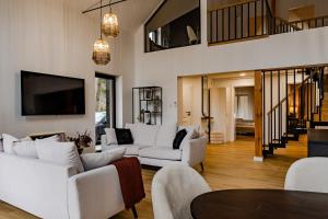 a living room with white furniture and a flat screen tv at Przystań Roztocze, nowoczesny dom z sauną i jacuzzi in Susiec