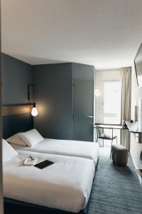 a hotel room with two beds and a table at Kyriad Metz Centre - Restaurant Moze in Metz