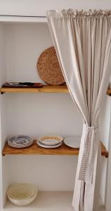 a shelf with plates and a curtain on it at COLOMBO casa per vacanze in corte salentina in Matino