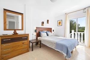 a bedroom with a bed and a dresser and a mirror at Villa KIP, private pool & jacuzzi surrounded by nature in Pinar de Campoverde +25 photos
