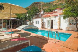ein Pool mit Sonnenschirmen und Stühlen neben einem Haus in der Unterkunft Pool House “El Estanco 14” in Vega de San Mateo