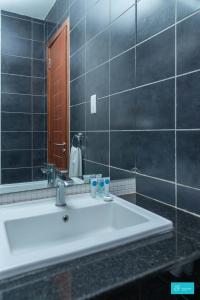 een badkamer met een witte wastafel en een spiegel bij Enclave Apartments Kilimani by YourHost, Nairobi in Nairobi