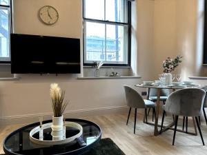a living room with a table and a tv at Stunning 2BR Apt in Central Manc in Manchester
