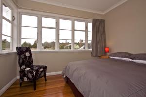 - une chambre avec un lit, une chaise et des fenêtres dans l'établissement The Mountain Pad - Rangataua Holiday Home, à Ohakune